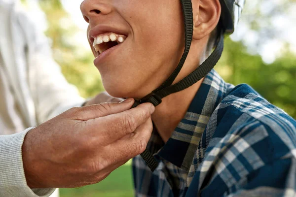 Father putting bicycle helmet on joyful son head — Foto Stock