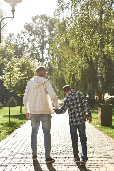 Back view of father and son hold hands and go — Foto de Stock