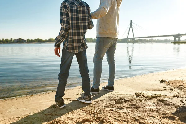 Baba ve oğul nehir kıyısında dinlenip el ele tutuşuyorlar.