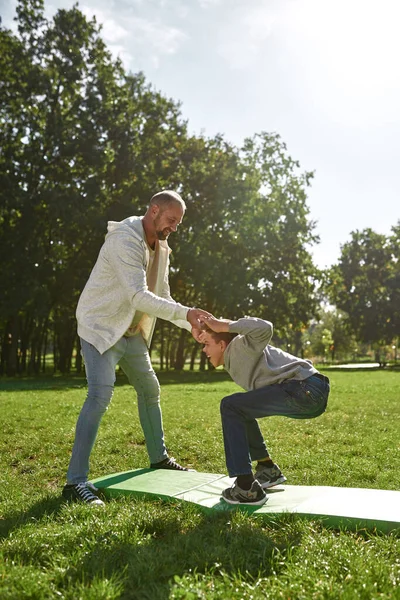 Baba, özürlü oğluna yardım et. Çimlerde mekik çek.