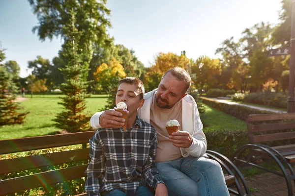 Kafkasyalı baba tatlı dondurmacı çocuğu besler.