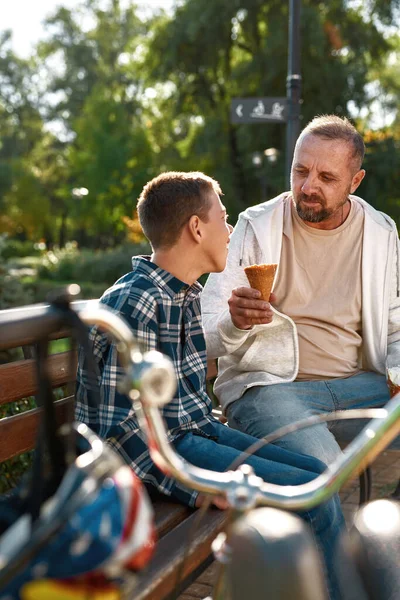 Kafkasyalı baba tatlı dondurmacı çocuğu besler.