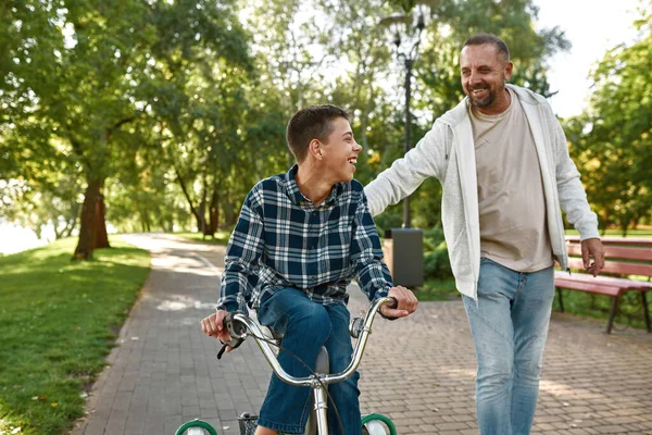 Baba oğluna beyin felci bisikletinde yardım eder.
