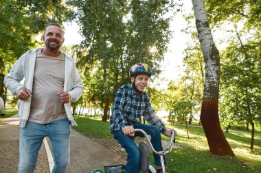 Mutlu baba bisiklet sürerken koşuyor.