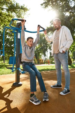 Baba oğluna beyin felci egzersizinde yardım ediyor.