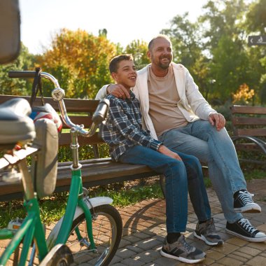 Serebral felçli baba ve oğlu bankta dinleniyor.