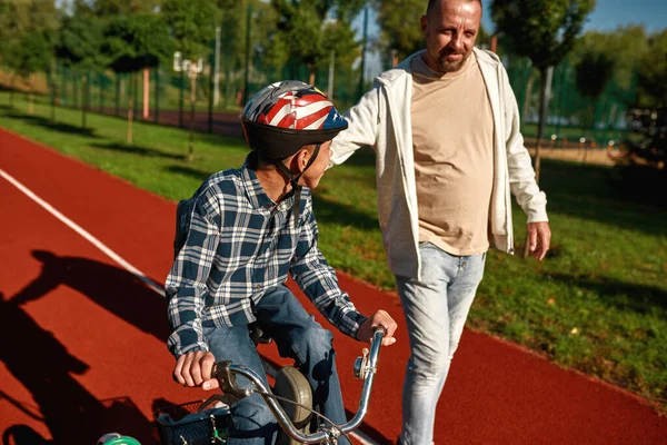 Táta chodit a pomáhat syn se zdravotním postižením na tříkolce — Stock fotografie