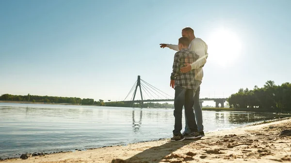 Baba, özürlü oğlanı eliyle işaret ediyor.