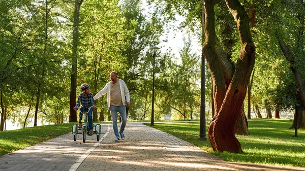 Father walk and help son ride tricycle on pavement — Φωτογραφία Αρχείου