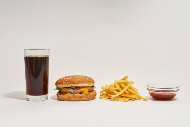 Soda, hamburger, patates kızartması ve sostan.