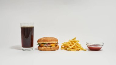 Soda, hamburger, patates kızartması ve sos kasede.