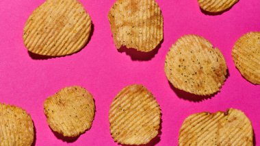 Patates cipsleri pembe arkaplanda izole edilmiş.