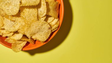 Sarı arka planda patates cipsli kase.