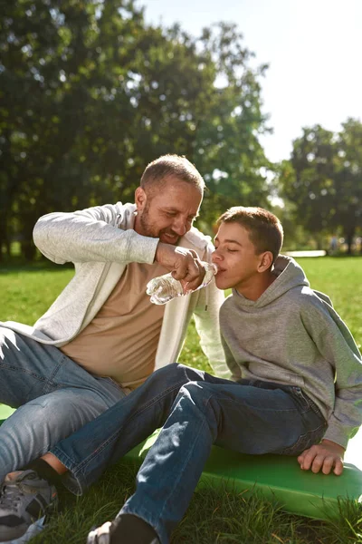 Dad giving water from bottle son with disability — Stok fotoğraf