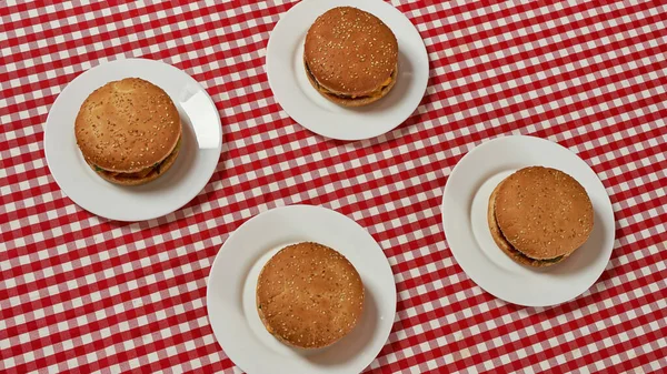 Vista superior de deliciosos hambúrgueres em pratos na mesa — Fotografia de Stock