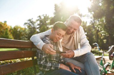 Laugh dad and son with disability watch smartphone