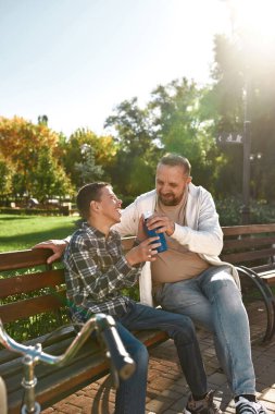 Father drink water laugh son with cerebral palsy