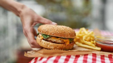 Hamburgerin seçici odağı bulanık kadın eli alıyor