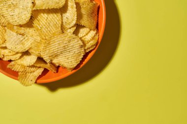 Sarı arka planda iştah açıcı cipsler ile kase