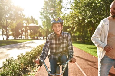 Adam koşuyor ve çocuk engelli bisikleti sürüyor.
