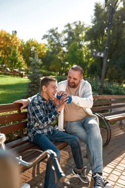 Father giving drinking water son with disability