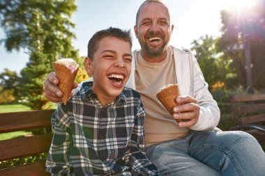 Laugh father and son with disability eat ice cream
