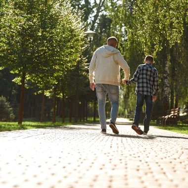 Özürlü baba oğul el ele tutuşun ve yürüyün.
