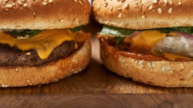 Partial close up of two burgers on cutting board