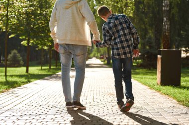Back of father and son with cerebral palsy walking