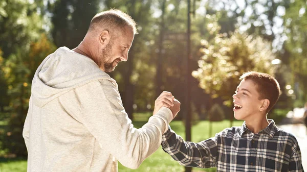 Father and son with disability shake hands in park — Stok fotoğraf