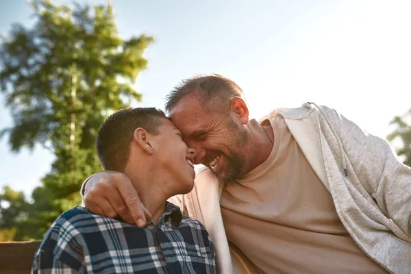 Happy father and son sitting head to head on bench — Foto Stock