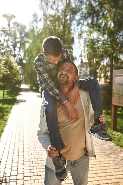 Dad carry on shoulders son with disability in park — Stok fotoğraf