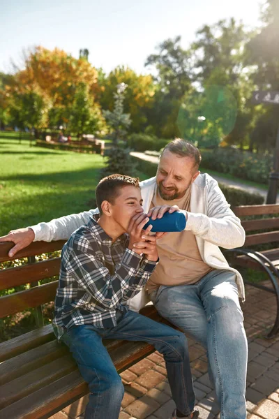 Smiling dad give drink water son with disability