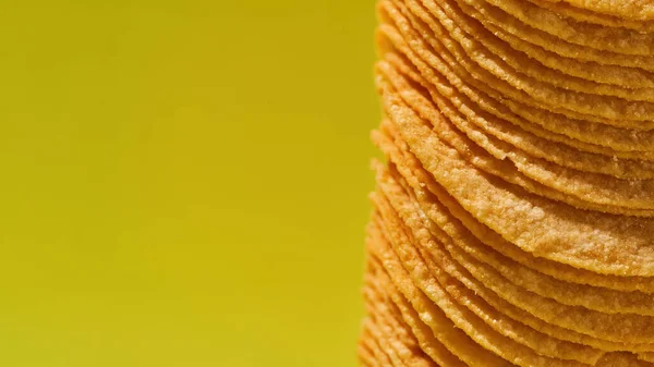 Close up of stack of chips on yellow background — Stockfoto