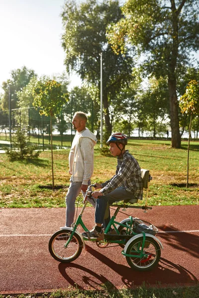 Side of dad near son with disability ride tricycle — Foto de Stock