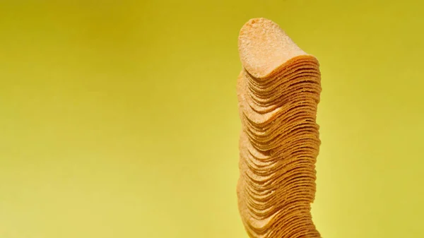 Gedeeltelijke stapel aardappelchips op gele achtergrond — Stockfoto