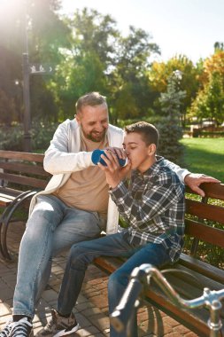 Caring father give drink water son with disability
