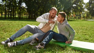Baba su ver oğlum. Çimenlikte sakat.