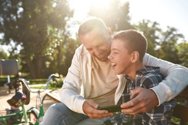 Dad watch smartphone near son with cerebral palsy