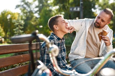 Dad wipe face of pleased teenage son with napkin