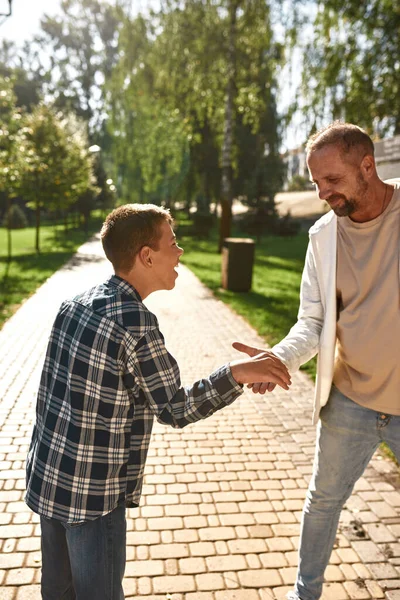 Europese vader en vrolijke tienerzoon schudden handen — Stockfoto