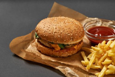 Hamburger, patates kızartması ve kağıt üzerinde sos.