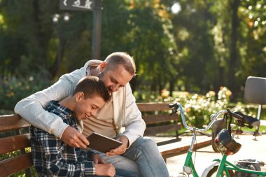 Engelli baba ve oğlu dijital tableti izliyor.