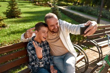 Dad and boy show victory sign during take selfie