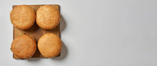 Bovenaanzicht van vier verse hamburgers op snijplank — Stockfoto