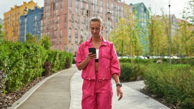 Atletik kız şehirde yürüyor ve cep telefonu kullanıyor