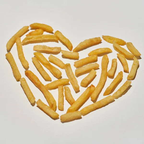 Chutné hranolky ve tvaru srdce na bílém pozadí — Stock fotografie