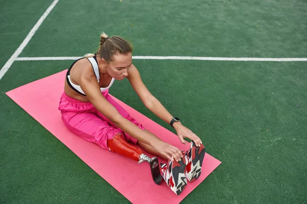 Girl has disability warm up legs on fitness mat