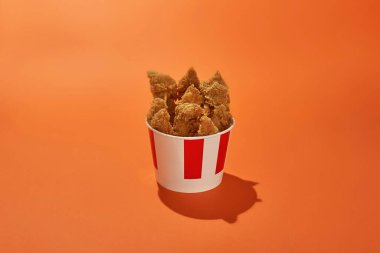 Fırında tavuk kanatları ve bacakları olan karton bir kova.