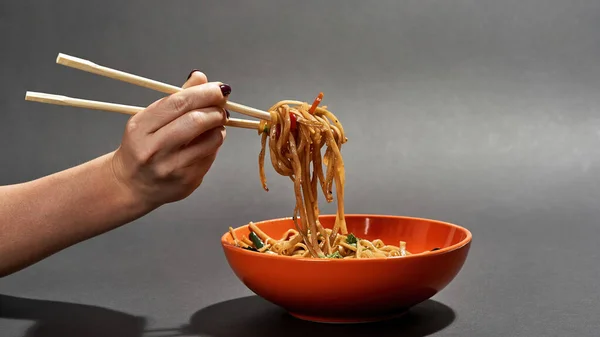 Female hand take noodles from bowl with chopsticks — Stock Photo, Image
